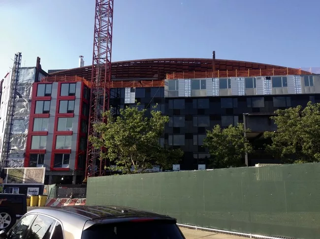 Modular housing has already obscured most of the east facade of Barclays Center, long before the building has reached its full height.