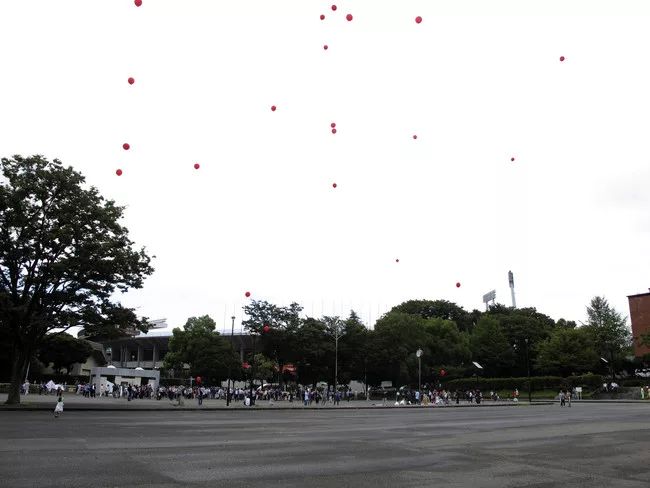 Protestors, including architect-activist Edward Suzuki (center), encircled the stadium carrying red balloons.<br /><div id='_mcePaste'>﻿﻿