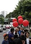 Protestors, including architect-activist Edward Suzuki (center), encircled the stadium carrying red balloons.<br /><div id='_mcePaste'>﻿﻿