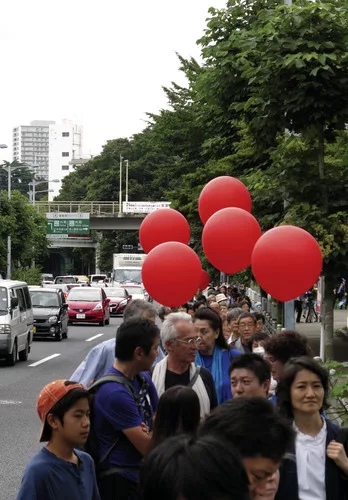 Protestors, including architect-activist Edward Suzuki (center), encircled the stadium carrying red balloons.<br /><div id='_mcePaste'>﻿﻿