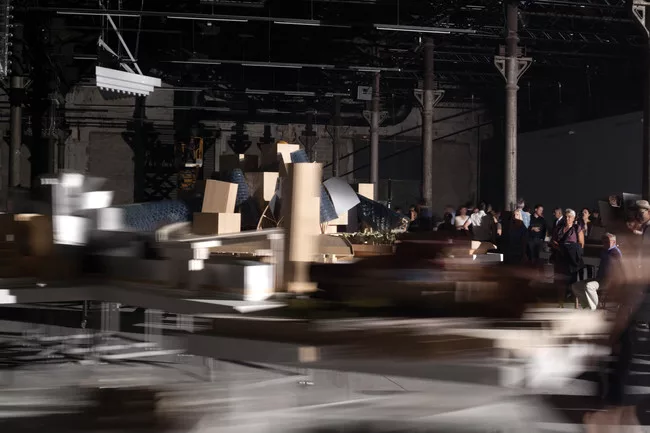 Perfromers push models of Frank Gehry's work around the exhibition according to a set of motions choreographed by artist Tino Sehgal.