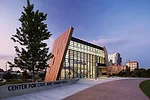 The Center’s angled exterior facade, composed of a mosaic of earth-toned phenolic-resin panels, frames a glass curtain wall.