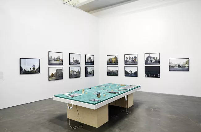 Rana Hamadeh's <em>The Big Board or ‘And Before It Falls It Is Only Reasonable To Enjoy Life A Little’</em> (2013) is surrounded by Hrair Sarkissian's photographs <em>Execution Squares</em