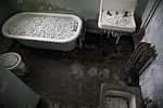 In some of the hospital cells, the artist has filled dilapidated toilets, sinks, and tubs with profusions of white porcelain flowers (<em>Blossom</em>). Like flourishing life poised to wash down the d