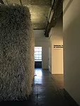 The exhibition includes a structure shaped like the perimeter of Birkenau, enclosing a space that can’t be seen or entered. The wall is covered with shredded paper, suggesting bits of logs and r