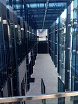Sou Fujimoto’s two-story porch, made of sheets of thick blue glass,  provides a facade for the half a dozen stores under construction behind  it.<div id='_mcePaste'>﻿﻿