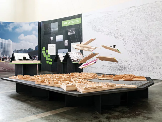 The six finalist designs are suspended over a model of Helsinki.