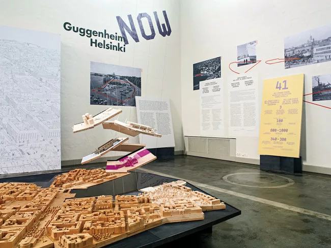 The six finalist designs are suspended over a model of Helsinki.