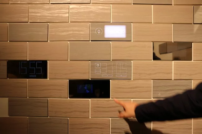 Conceptual wall tiles by Nissha transform with the touch of a finger from a marble stone or mirror finish to a digital interface where users can adjust temperature or access other home applications co