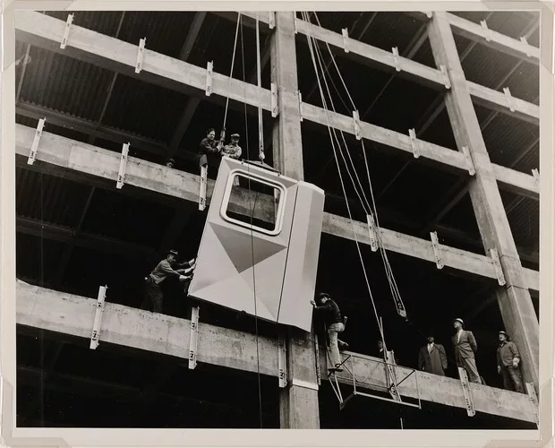 Workmen installing the first aluminum panel, 1951; gelatin silver print.