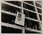 Workmen installing the first aluminum panel, 1951; gelatin silver print.