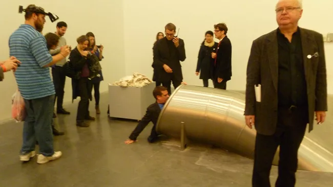 A visitor wears a pair of H'ller's vision-inverting prism goggles, while another climbs into <em>Untitled (Slide)</em>, 2011