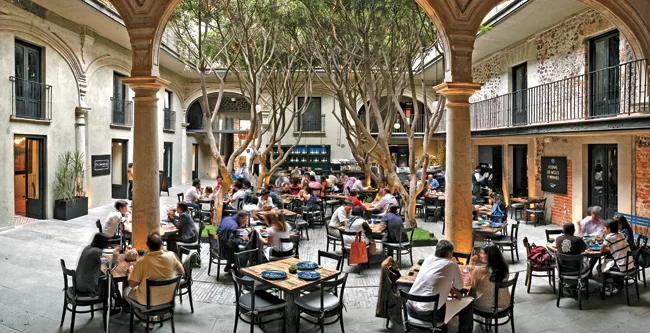A stand of trees shades a restaurant patio in the building's primary courtyard.