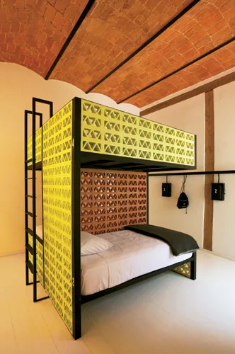 In some of the hotel suites and the hostel rooms, the designers inserted new floor plates above the existing ceilings to preserve their historic materials. They paid homage to the original masonry wit