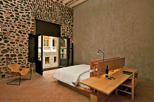 In some of the hotel suites and the hostel rooms, the designers inserted new floor plates above the existing ceilings to preserve their historic materials. They paid homage to the original masonry wit