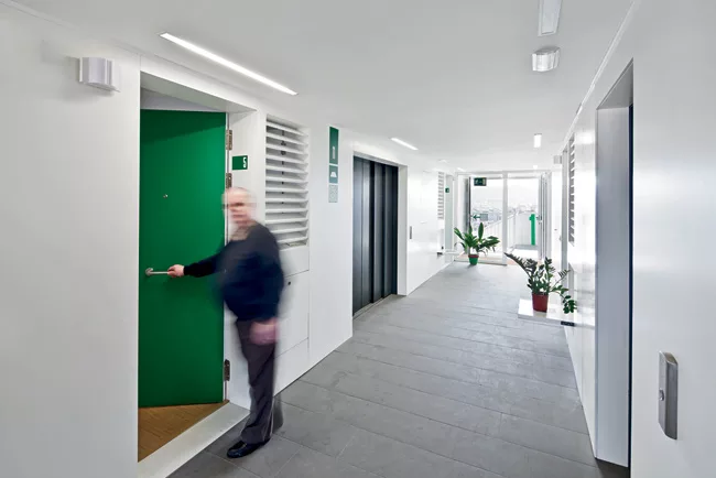 Corridors are extra-wide, with glazed ends opening to the outdoor stairs. The apartment units' louvered windows open to allow cross-ventilation.