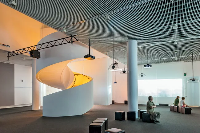 A glowing spiral stair, made of poured-in-place concrete, connects the permanent-exhibition level, temporary exhibitions, and staff offices and conference areas.