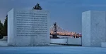 The Queensboro Bridge glows behind a granite block on which is engraved text from FDR's 'Four Freedoms' speech.