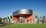 The color of the concrete panel skin shifts from sea-foam green to silver and terra cotta to articulate a curved corner entry.
