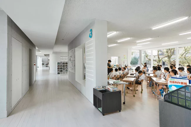Windowlike cutouts in the L-shaped walls connect teaching and circulation areas and display student work.