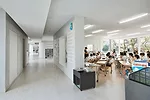 Windowlike cutouts in the L-shaped walls connect teaching and circulation areas and display student work.