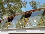 Glass clerestory panels are held in place by aluminum 'spiders' and can pivot out to project sound for outdoor performances. An actuator used in airplanes puts the glass panels in motion.