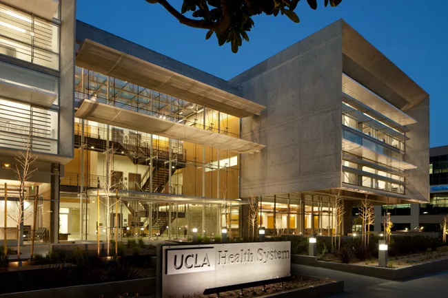 The architect divided the center’s massing between two concrete pavilions; the southern volume cantilevers 25 feet over a first-floor waiting room. A central glass lobby glows at night.
