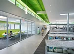 A long streetlike axis extends along the edge of the reading room; a pressed polymer finish in which shredded magazines are embedded covers the metal shelves.