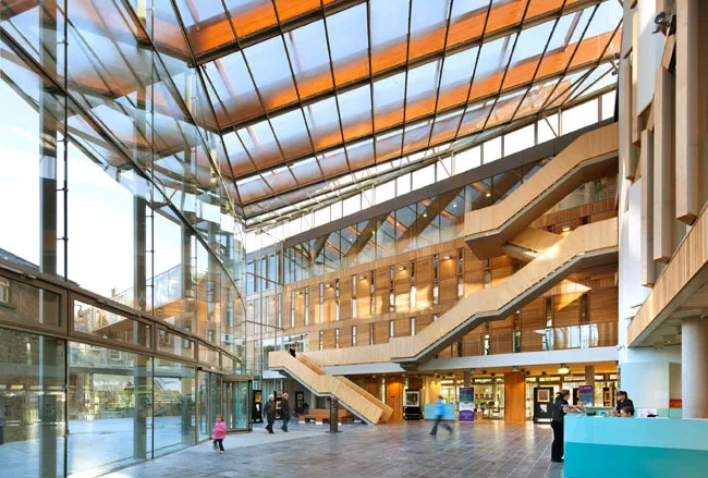 A glass-fronted atrium serves as a hub for the complex of buildings and provides access to various government agencies. Library visitors climb the internal stair to the second floor.