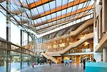A glass-fronted atrium serves as a hub for the complex of buildings and provides access to various government agencies. Library visitors climb the internal stair to the second floor.