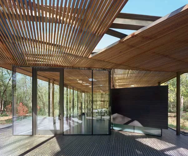 The architect used wood slats and floor-to-ceiling glass to orchestrate a subtle medley of visual effects, ranging from the transparent to the shaded to the reflective.