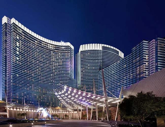 The edges of sunshades on the sawtooth-shaped facade of the Aria Resort & Casino catch light from floodlights placed on the hotel's vast podium. These lights, together with fluorescent fixtures illumi