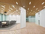 The wood-veneer aluminum-plank ceiling in the lobby is inset with linear fluorescent fixtures that emphasize openness and continuity and also fulfill the varied luminance needs of the different areas 