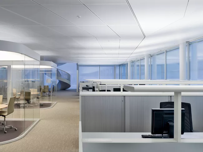 Maki collaborated with Licht Kunst Licht to develop hybrid luminaires integrated into the office furnishings: Small, glass-enclosed “private rooms” are topped by illuminated stretch ceilin