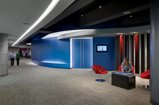 SmithGroup outlined the portal to the Envisioning Center—an auditorium-like space—with LEDs behind a translucent acrylic. A ribbon of the undulating blue wall bows in and out to mimic the