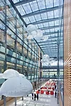 Photovoltaic panels top a glazed central atrium, serving as shading devices while generating electricity.