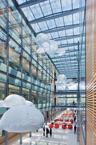 Photovoltaic panels top a glazed central atrium, serving as shading devices while generating electricity.