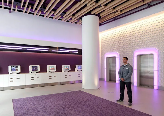 In the lobby, white LEDs wash a textured wall. Purple LEDs illuminate elevator door surrounds.