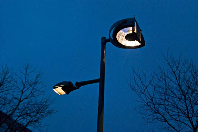 Shadow play Custom fixtures at the tops of the poles (left) face away from the street and house a series of mirrors and projectors that distribute a playful array of vertical and horizontal light patt