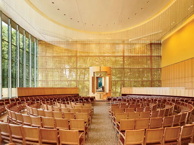 The architects and lighting designers collaborated to create a custom wood screen for the east-facing window wall behind the ark that delivers a subtle, filtered light during the day (slide 3) and an 