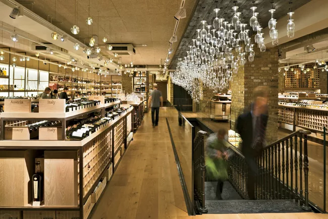 Inside the entrance, a champagne-hued material palette sparkles by the light of delicate, bubblelike glass pendants and the sommelier-glasses “chandelier.”