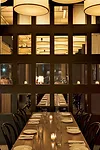 The private dining area (left) features a wall grid inset with a playful mix of mirrors and windows. These either reflect the barrel shades within the room or provide glimpses of the ceiling grid&mdas