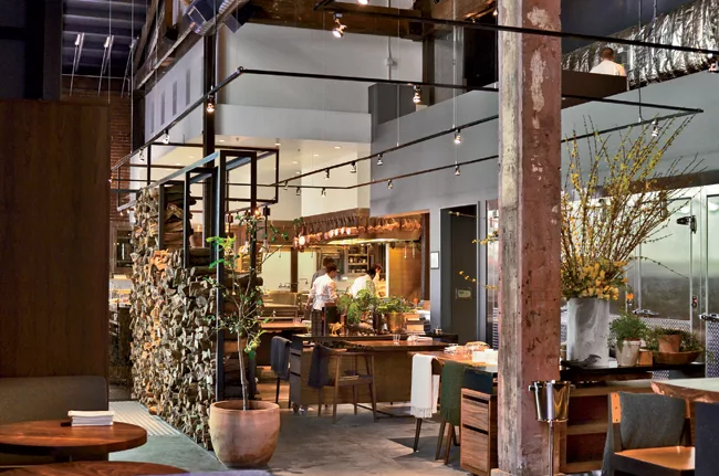The designers dropped the ceiling over the kitchen to a height of 12 feet, painted it white, and concealed HVAC, grease traps, and plumbing above the soffit. A narrow concrete loft that houses wine st