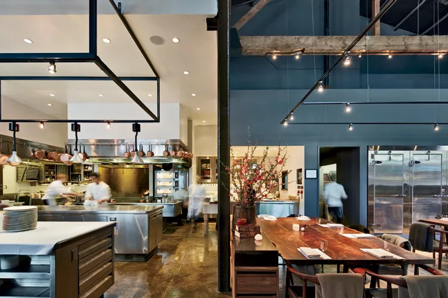 Though the bright white kitchen commands attention in the loftlike space (left) the dining tables are also bathed in light to stage a personal experience for guests.