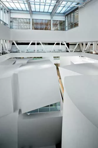 Fissures in the lids of the atrium's volumes containing chamber ensemble rooms allow daylight to filter from above to the interiors.