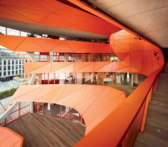 Ringed by bands of aluminum panels, the west-facing void cuts deep into the cube. This elliptical opening not only provides striking views; it also brings ample daylight into the facility and channels