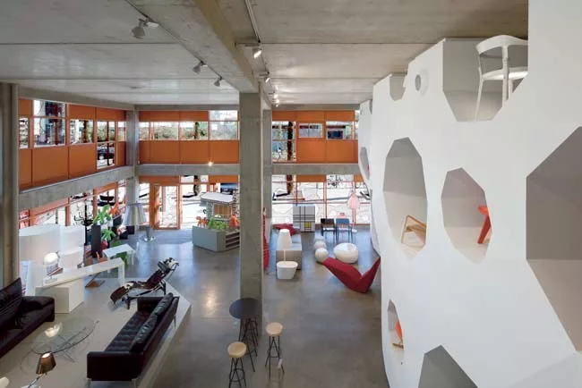 A 9,690-square-foot furniture showroom occupies the ground floor and mezzanine. The loftlike space features a dramatic, 184-foot-long display wall with various shaped holes; its design refers to the b