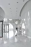 In the lobby, the architects designed the powder-coated aluminum reception desk to echo the curve of the walls and blend in with the luminescent white marble floors.