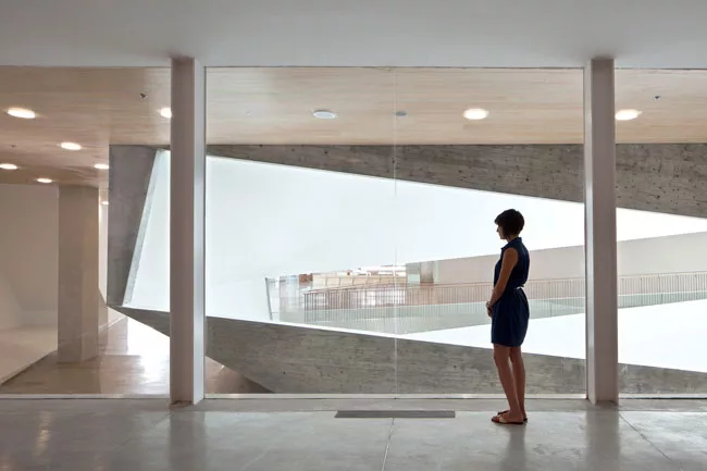 Long rectangular cuts in the Lightfall offer views through the central void and into galleries on the opposite side.