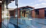 A trio of copper-clad pavilions rise above the plane of a reflecting pool, while linear skylights set in the pool bring daylight to galleries below.